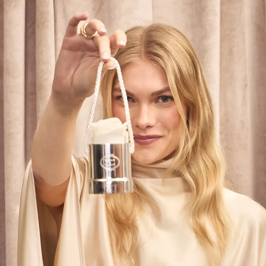 A woman holding the silver-plated Annual Edition Ornament with a white Eternity® Rose by its braided cord