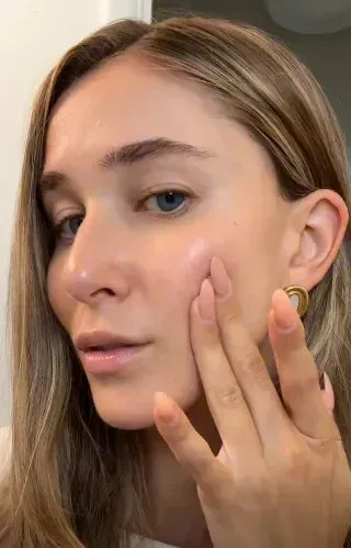 Close-up of Becca gently touching her cheek