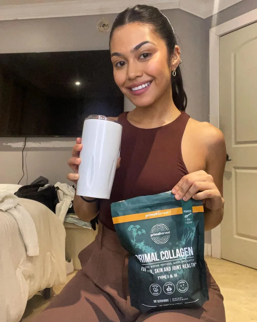 Woman holding Primal Collagen and a tumbler