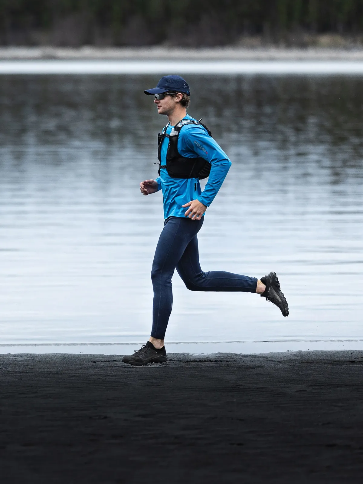 Runner wearing the Stellar Tech Long Sleeve in Blue by a lakeshore