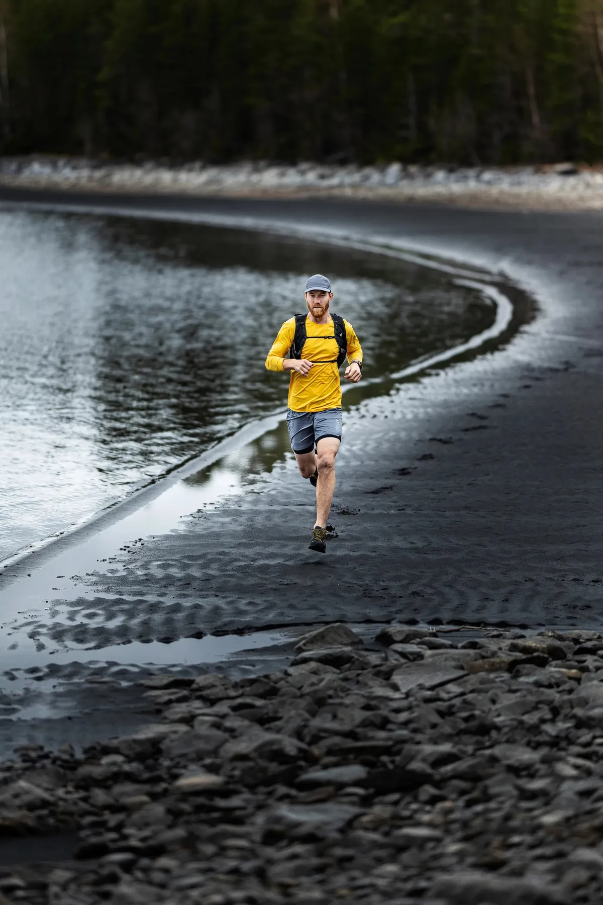 Runner wearing the Stellar Tech Long Sleeve in Yellow on a rocky shore
