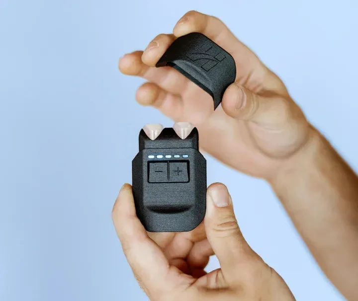 Hands holding the compact VeRelief Prime device and its protective cap