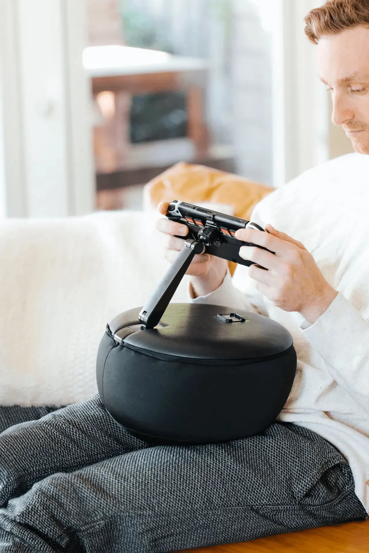 Gamer adjusting the Gaming Pillow’s articulated mount on a couch